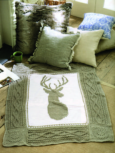 a bed covered in pillows and blankets with a deer head drawn on the pillow cover