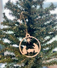 a christmas ornament hanging from the top of a tree with a nativity scene on it