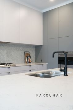 a kitchen with white cabinets and marble counter tops, including a black faucet