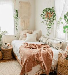 a bedroom with white walls and plants in the window sill, bedding is made from natural materials