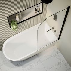 a white bath tub sitting on top of a bathroom floor next to a sink and mirror