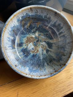 a bowl sitting on top of a wooden table next to a potted planter