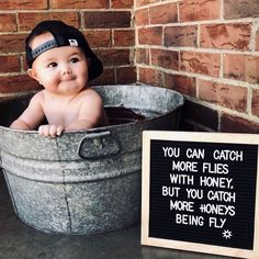 a baby in a bucket with a sign that says you can catch more flies with honey, but you catch more honeys being fly