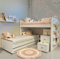 a child's bedroom with two bunk beds and a rug on the floor in front of it