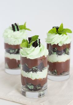 three desserts in small glass containers with mint leaves on top