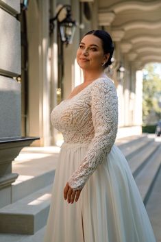 a woman in a white dress is standing on some steps and posing for the camera