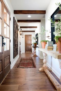 a long hallway with potted plants on either side of the door and an area rug on the floor