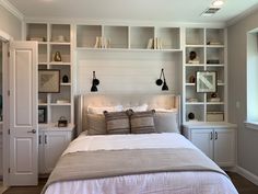 a bedroom with built - in shelving and pillows on the headboard, along with a large bed