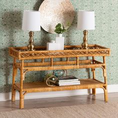 a rattan console table with two lamps and a round mirror on the wall behind it