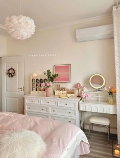 a bedroom with white furniture and pink decor on the walls, along with a large mirror