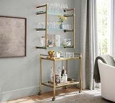 a gold bar cart filled with glasses and bottles