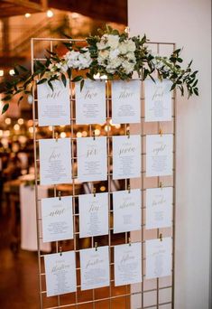 a table plan with white flowers and greenery is displayed on a gold metal frame