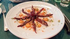 a white plate topped with lots of food on top of a green tablecloth next to silverware