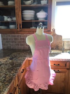 a mannequin wearing a pink apron in a kitchen