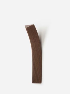 a wooden object is hanging on the wall in front of a white background, it looks like a curved piece of wood