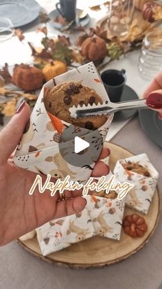 a person holding a cookie in front of a table full of plates and napkins