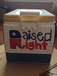 a cooler with the word raised right on it sitting on a table next to a window