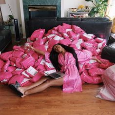 a woman is laying on the floor covered in pink bags with her legs spread out