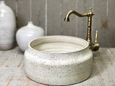 a white sink sitting on top of a counter next to two vases and a faucet