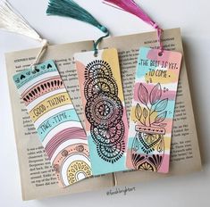 three bookmarks with tassels on top of an open book