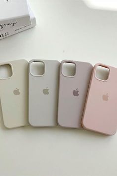 four iphone cases sitting next to each other on top of a white table with a box in the background