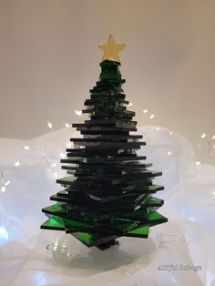 a green glass christmas tree sitting on top of a white table