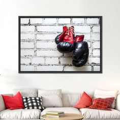 two black and red boxing gloves hanging on a brick wall above a white couch in a living room