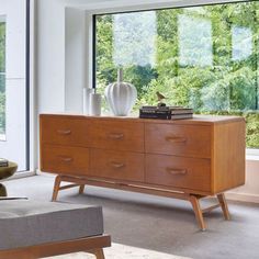 a living room scene with focus on the dresser and large window overlooking the trees outside