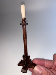 a hand holding a small wooden candle holder with a lit candle on it's end