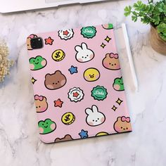 a pink ipad case with various cartoon characters on it and a phone next to it