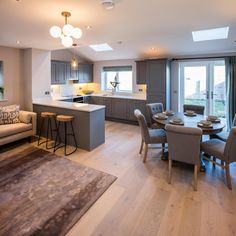 a large open kitchen and living room with wood flooring in the middle, along with an island table surrounded by gray chairs