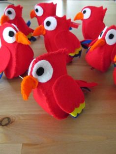 several red birds sitting on top of a wooden table next to each other with googly eyes