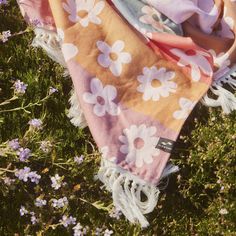 a blanket laying in the grass with flowers on it