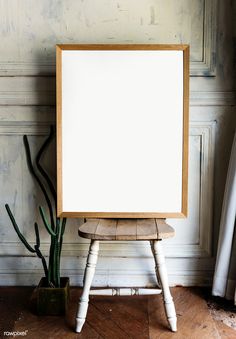 an empty wooden frame sitting on top of a wooden chair next to a potted plant