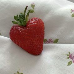 a red strawberry sitting on top of a white sheet