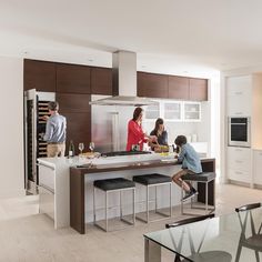 three people in a kitchen preparing food and wine for the guests to enjoy them at