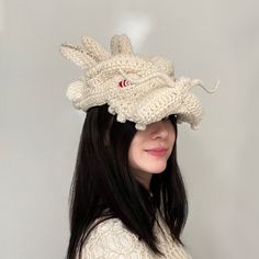 a woman wearing a knitted hat with a dragon on it's head and long black hair