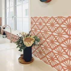 a vase filled with flowers sitting on top of a counter next to a sink and window