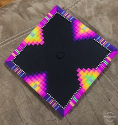 a black square with multicolored squares in the center on top of a table