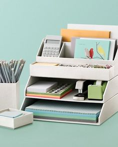 an office desk with a calculator, pen holder and pencils