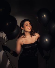 a woman in a black dress holding balloons