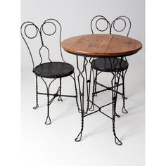 two chairs and a table made out of wrought iron with wood top on white background