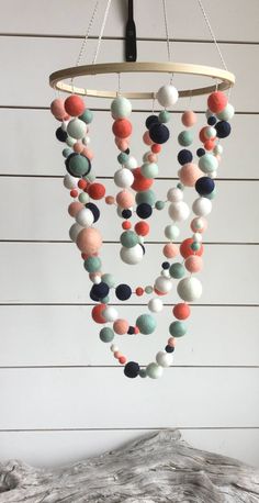 a mobile made out of felt balls hanging from a ceiling fixture in front of a white wall