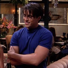 the young man and woman are sitting together in front of a table with flowers on it