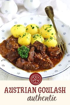 a white plate topped with meat and potatoes covered in gravy next to a fork