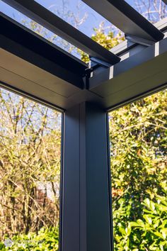 an open window showing the view of trees and bushes from it's outside area