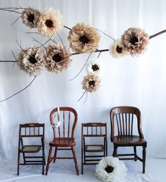 three wooden chairs with flowers hanging from the back, and one chair has a flower arrangement on it