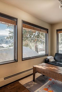 a living room filled with furniture and two windows covered in wintery snow outside the window