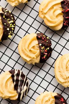 several cookies with frosting and sprinkles on a cooling rack