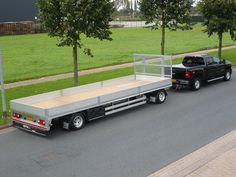 two trucks are parked on the side of the road near some trees and grass in front of a field